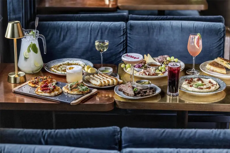 Une table garnie de plats et de boissons colorées est mise en scène dans un intérieur soigné.
