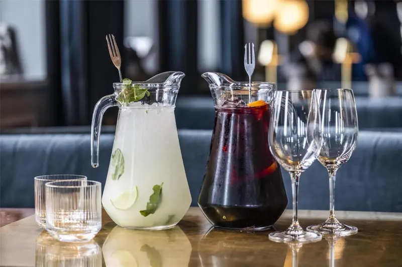 Une table présente des carafes de boissons et des verres.