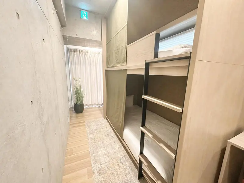 Une chambre avec des lits superposés et un tapis clair.