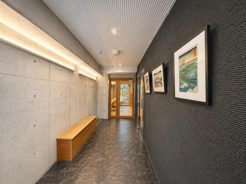 Un long couloir moderne avec des œuvres d'art au mur et un banc en bois.