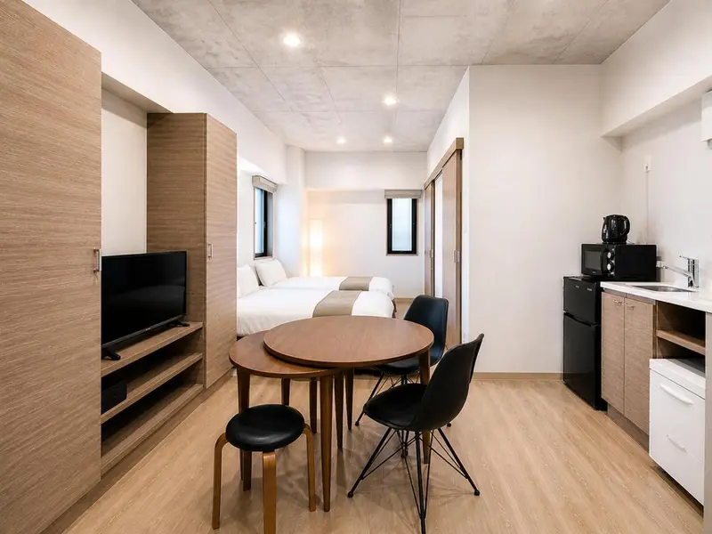 Une chambre avec un lit, une table ronde et une kitchenette.