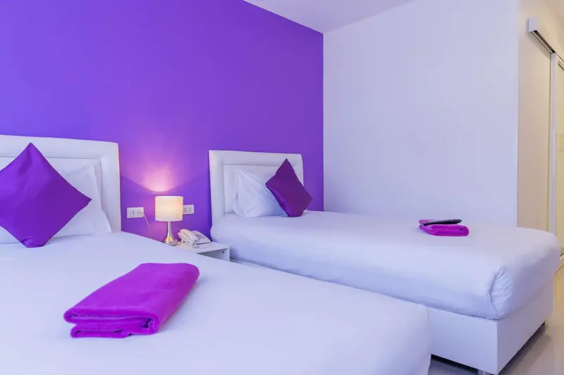Deux lits simples avec des couvertures violettes dans une chambre lumineuse.