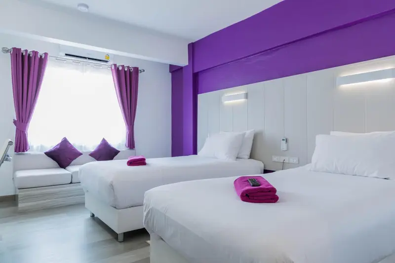 Chambre lumineuse avec deux lits simples et une décoration violette.