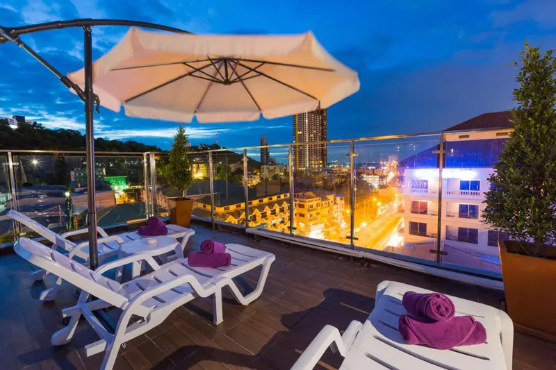 Terrasse avec transats et vue sur la ville illuminée au crépuscule.