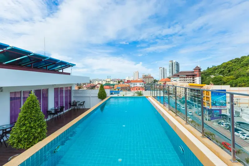 Piscine rectangulaire sur un toit avec vue sur la ville et la végétation.