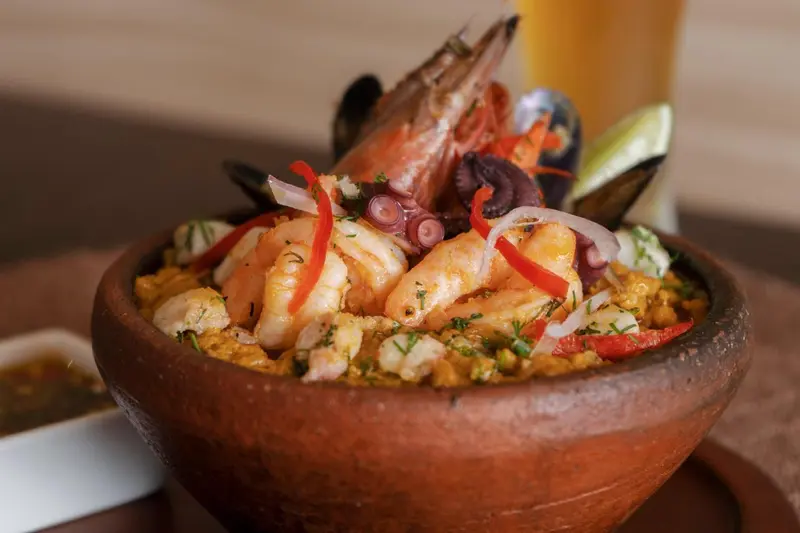 Assiette de fruits de mer et de riz présentée dans un plat en terre cuite.
