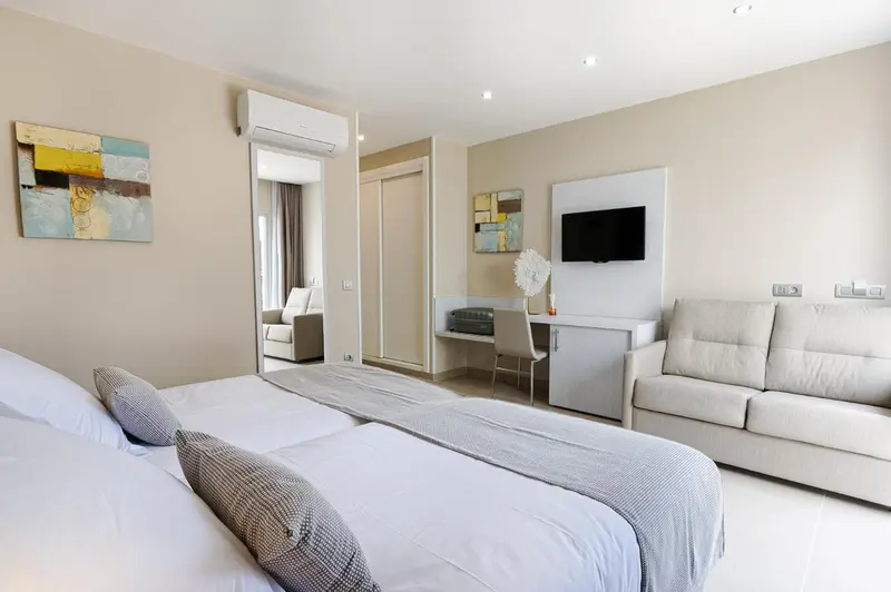 Une chambre lumineuse avec un lit double, un canapé et un espace bureau.