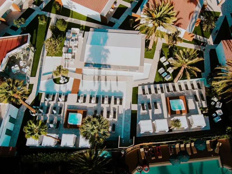 Vue aérienne d'un complexe hôtelier avec des piscines et des palmiers.