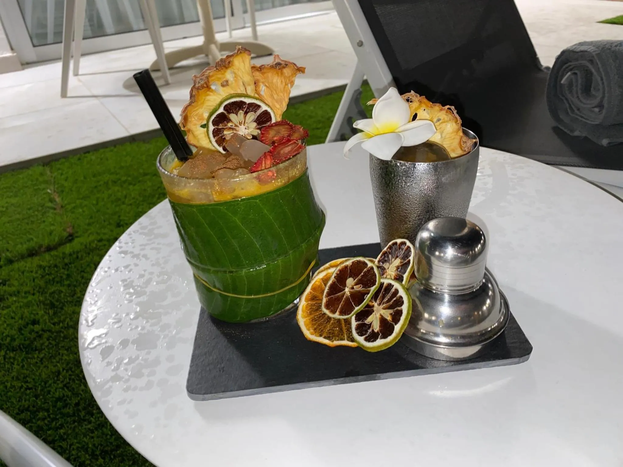 Deux cocktails exotiques présentés sur une table blanche avec une décoration florale et fruitée.