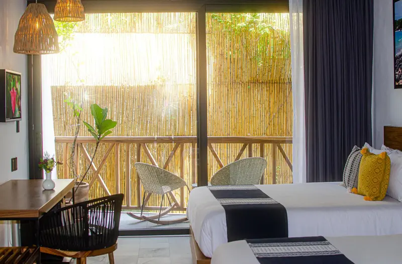 Une chambre lumineuse avec un lit et un coin repas donnant sur une terrasse.