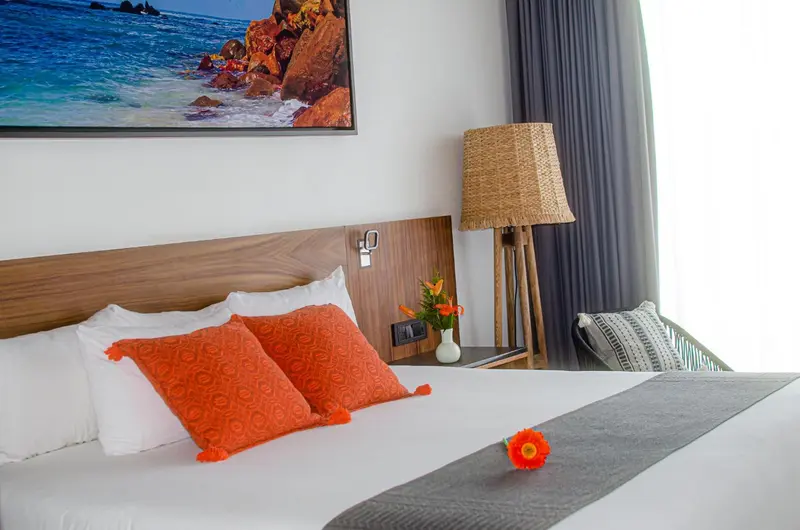 Une chambre lumineuse avec un grand lit décoré de coussins.