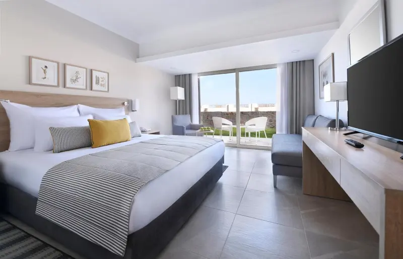 Une chambre lumineuse avec un grand lit et un accès à une terrasse.