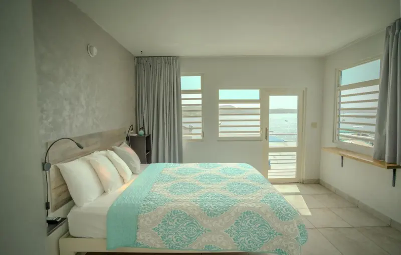 Une chambre lumineuse avec un grand lit donnant sur une vue mer.