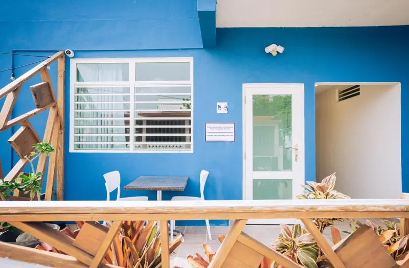 Façade bleue d'un bâtiment avec une table et des chaises en bois.