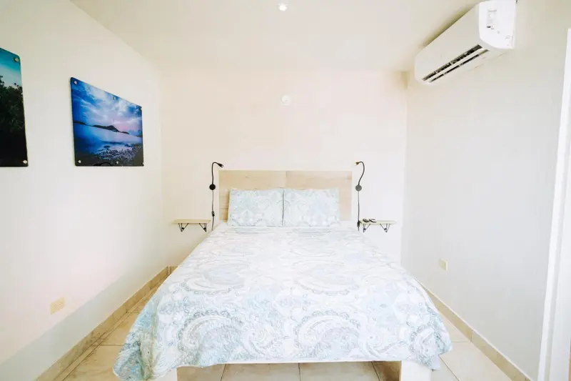 Une chambre lumineuse avec un grand lit recouvert d'une courtepointe claire.