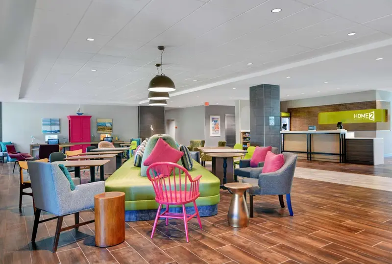 Un espace de détente lumineux avec des fauteuils colorés et un comptoir d'accueil.
