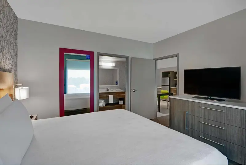 Une chambre d'hôtel lumineuse avec un lit blanc et un accès à une salle de bain.