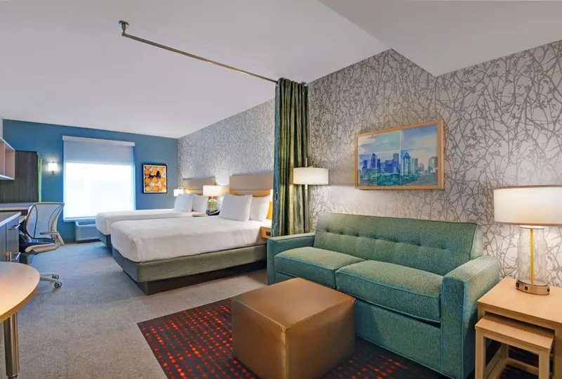 Une chambre lumineuse avec un grand lit et un canapé vert.