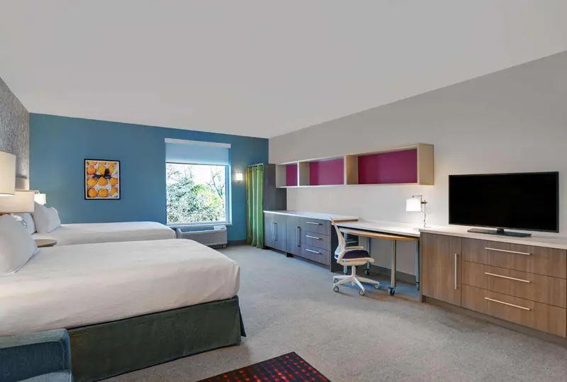 Une chambre d'hôtel lumineuse avec deux lits et un espace bureau.