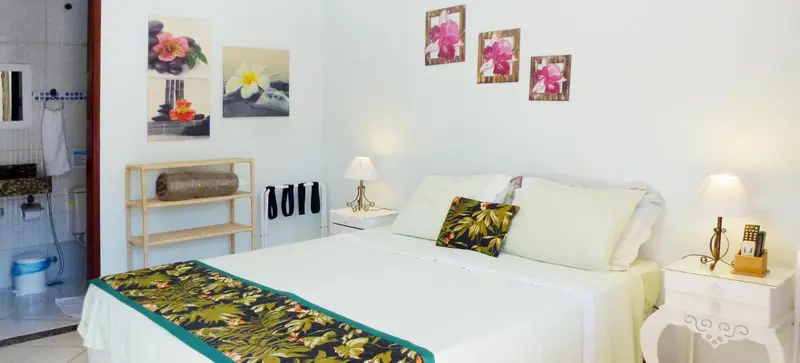 Une chambre lumineuse avec un lit double et des tableaux floraux.