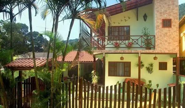 Bâtiment vert et blanc avec balcon fleuri et végétation tropicale.