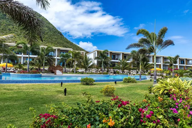 Vue d'un complexe hôtelier avec piscine et végétation luxuriante au premier plan.