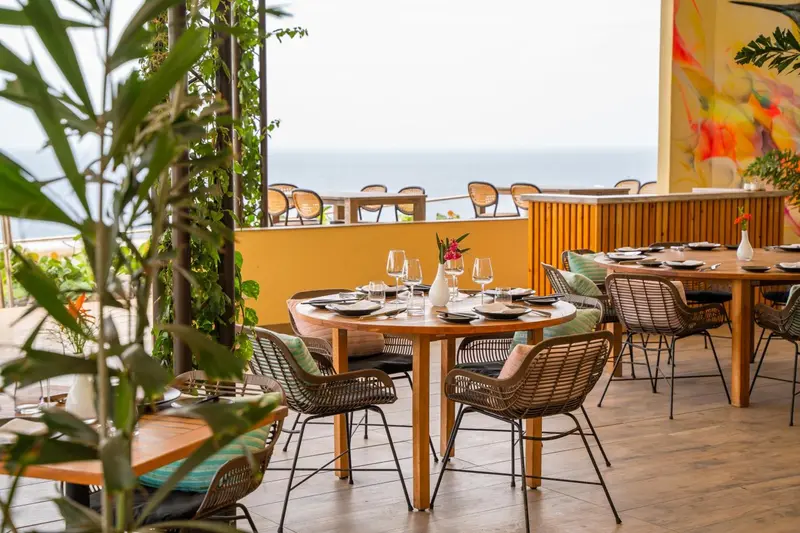 Tables dressées sur une terrasse ensoleillée avec vue sur la mer.