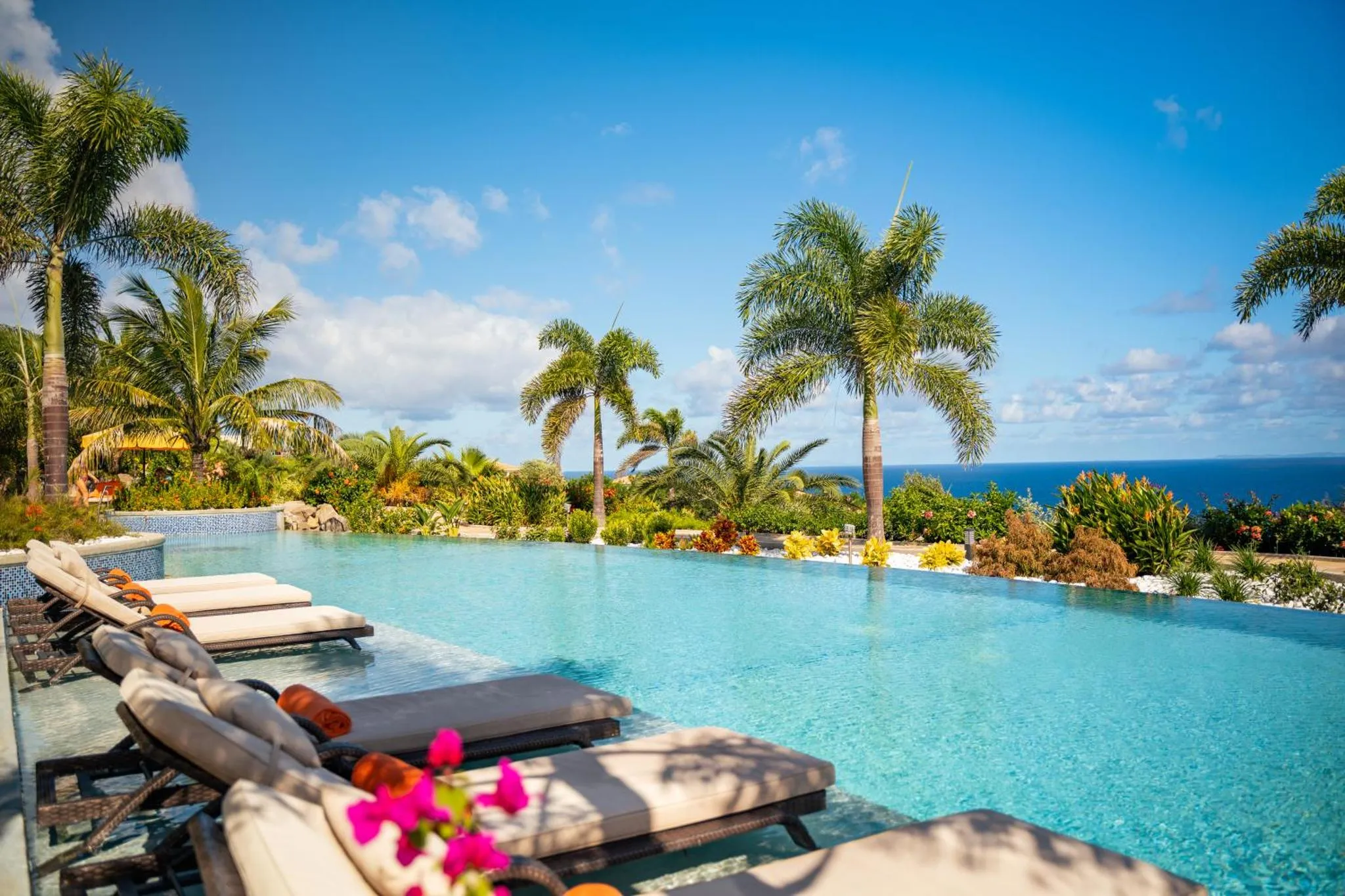 Transats alignés au bord d'une piscine à débordement avec vue sur la mer.