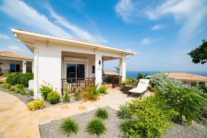 Façade d'une maison blanche avec une terrasse et une vue sur la mer.