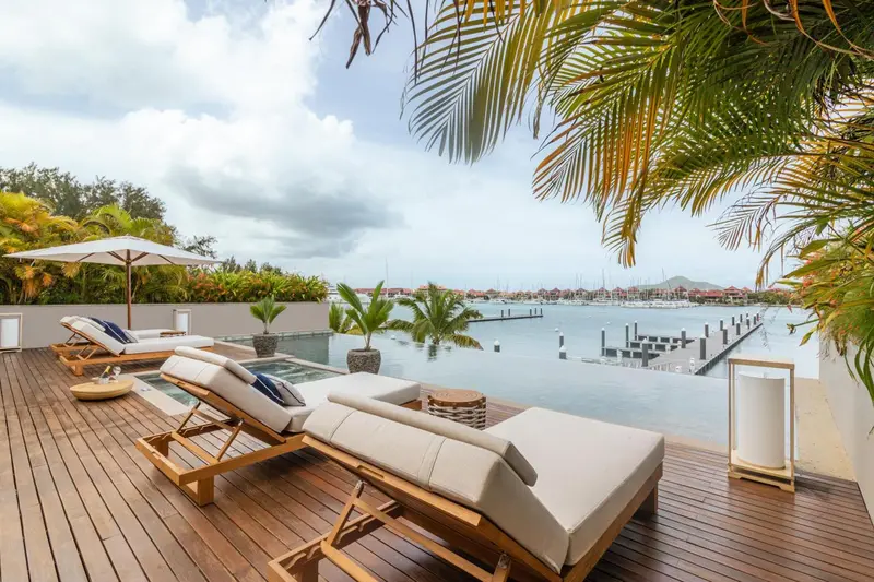 Terrasse en bois avec transats et jacuzzi face à la mer.
