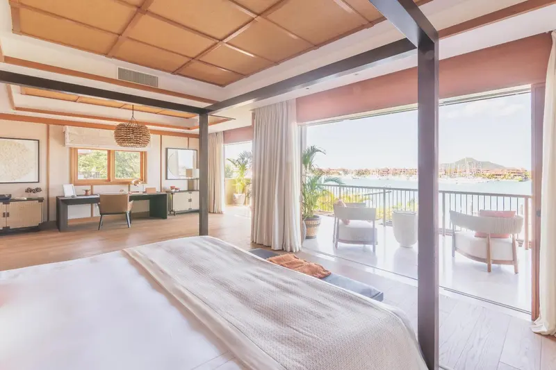 Une chambre spacieuse avec un lit à baldaquin donnant sur une terrasse et une vue sur la mer.