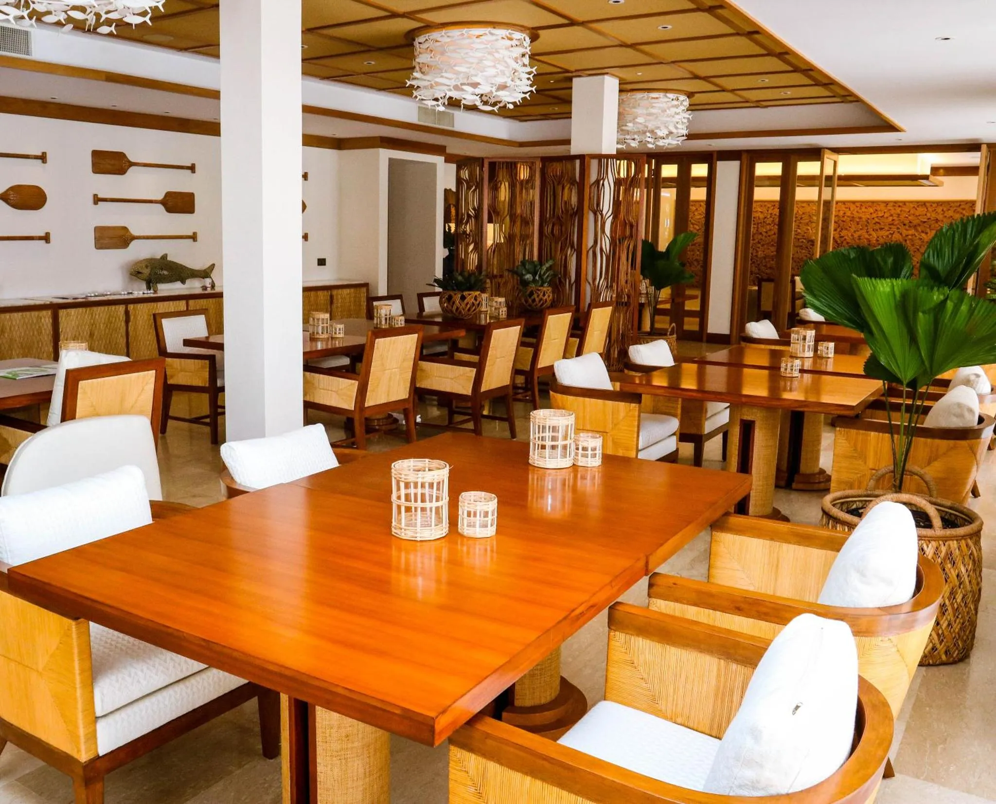 Une salle de restaurant lumineuse avec des tables en bois et des chaises en rotin.