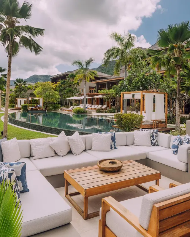 Espace de détente extérieur avec canapés et table basse près d'une piscine.