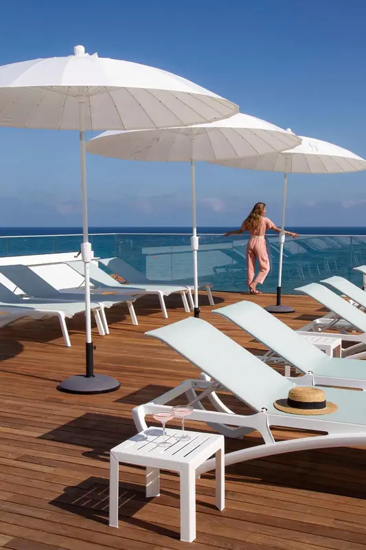 Terrasse ensoleillée avec transats et vue sur la mer.
