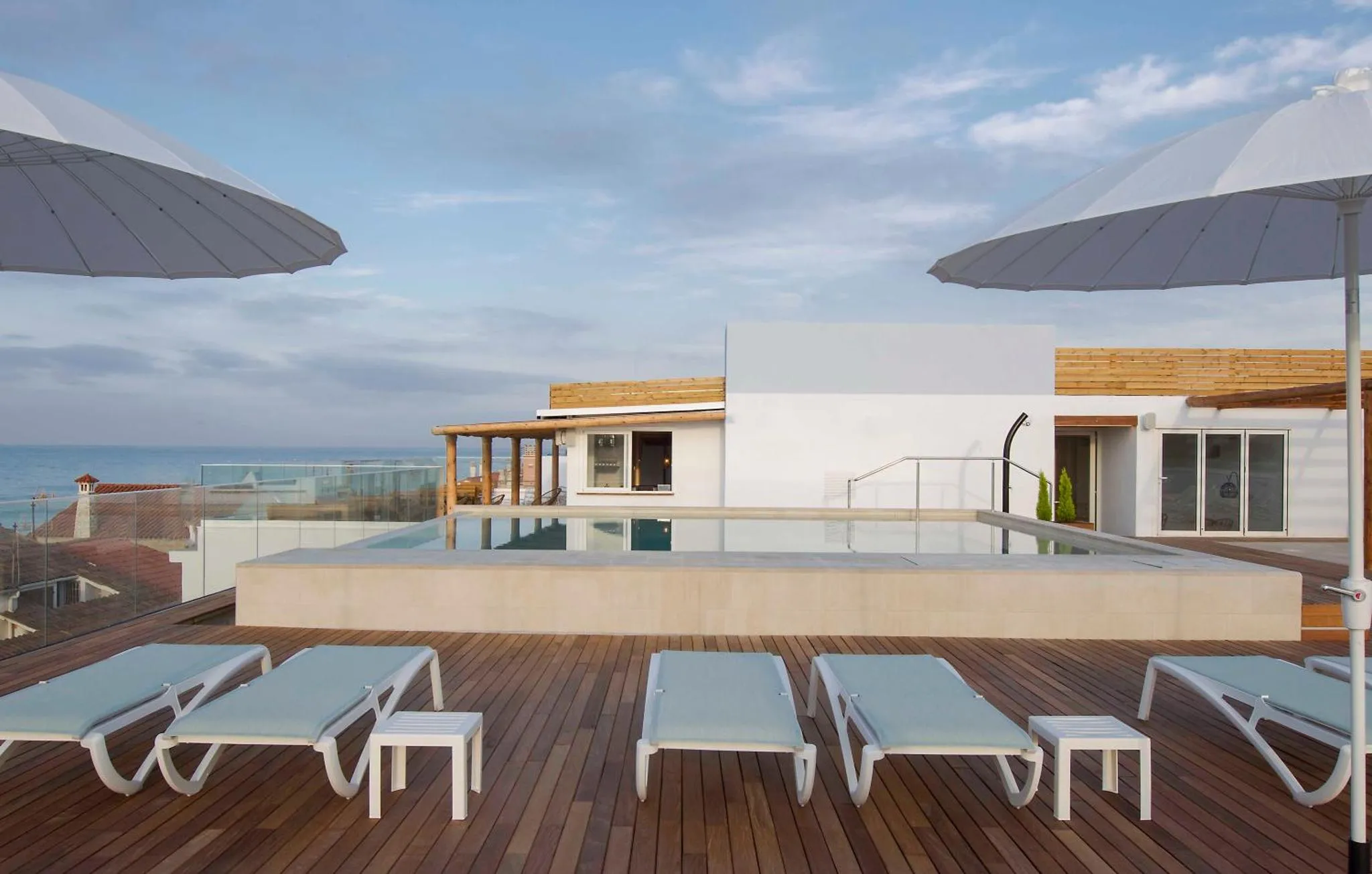 Terrasse avec transats et piscine surplombant la mer.