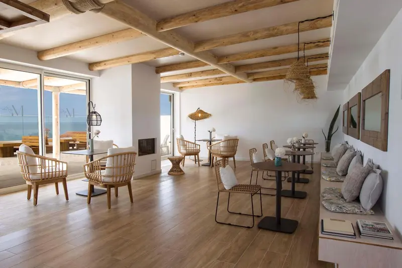Espace de détente lumineux avec mobilier en bois et vue sur la mer.