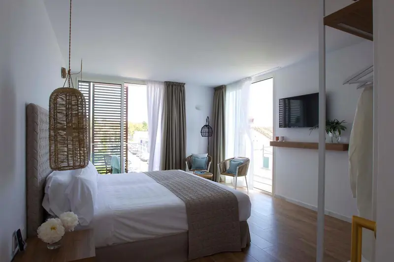 Chambre lumineuse avec un grand lit et un accès à une terrasse.