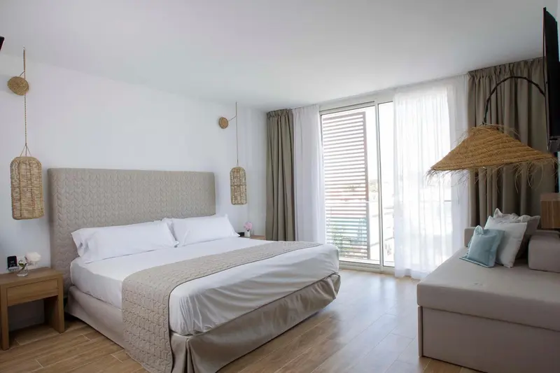 Une chambre lumineuse avec un grand lit et un coin salon.