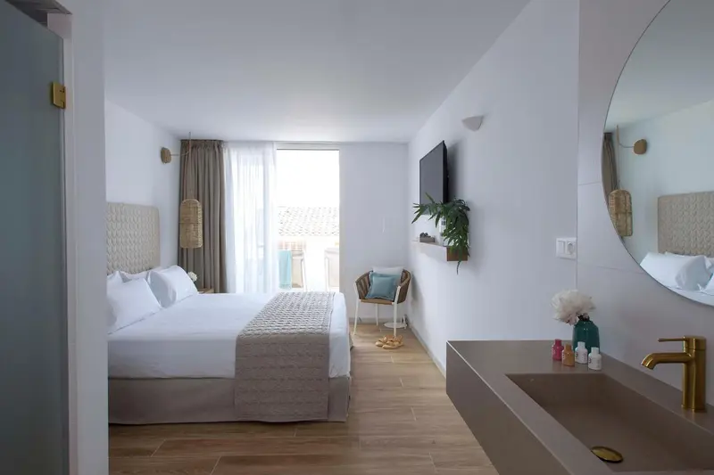 Chambre lumineuse avec un grand lit et un accès à une terrasse.
