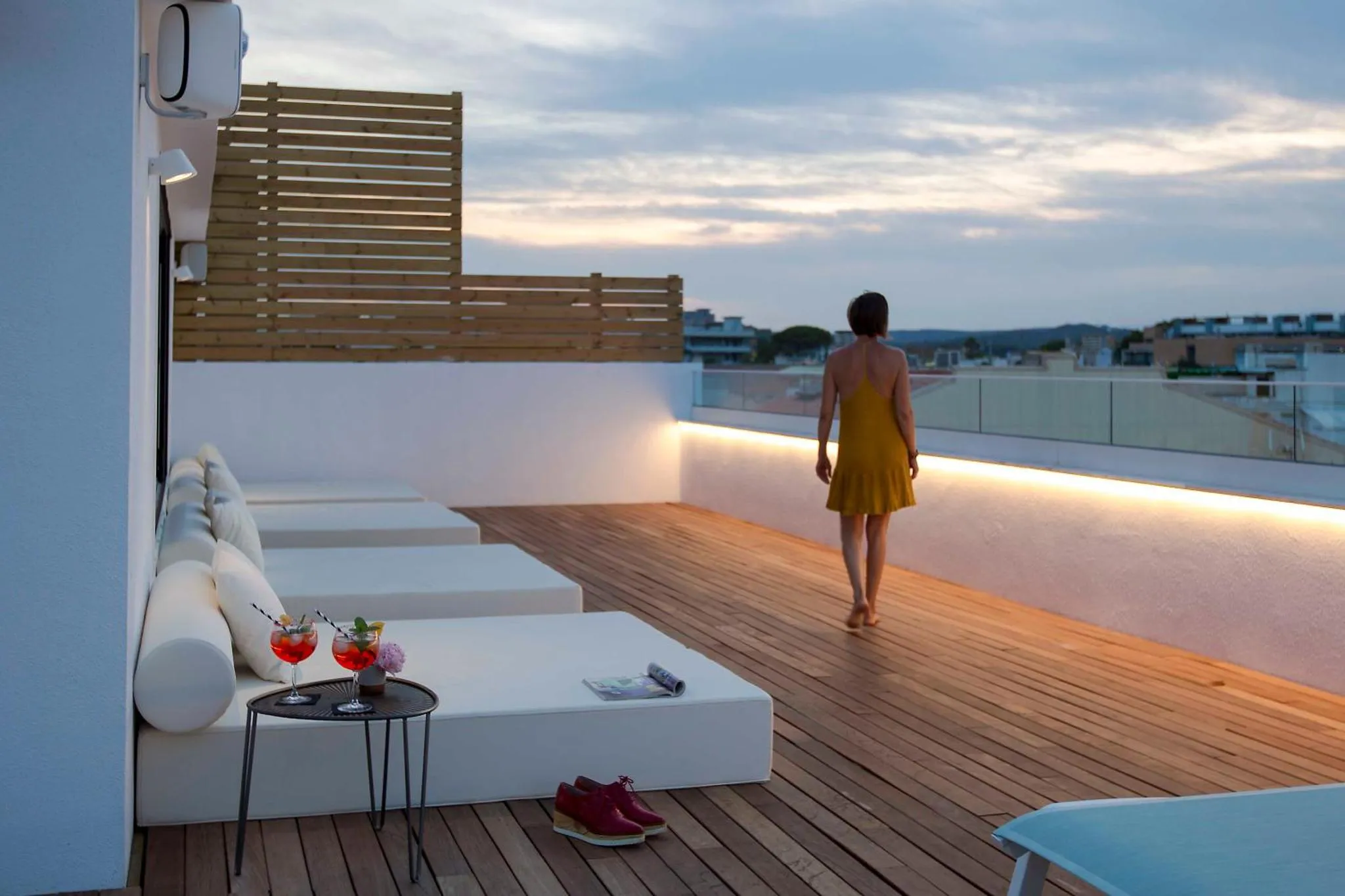 Une femme se promène sur une terrasse avec des transats et une vue sur la mer.