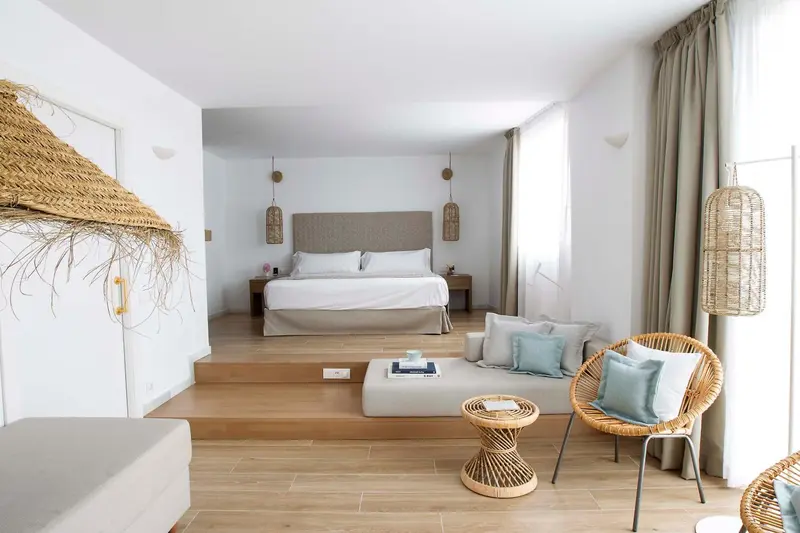 Une chambre lumineuse avec un grand lit et un coin salon.