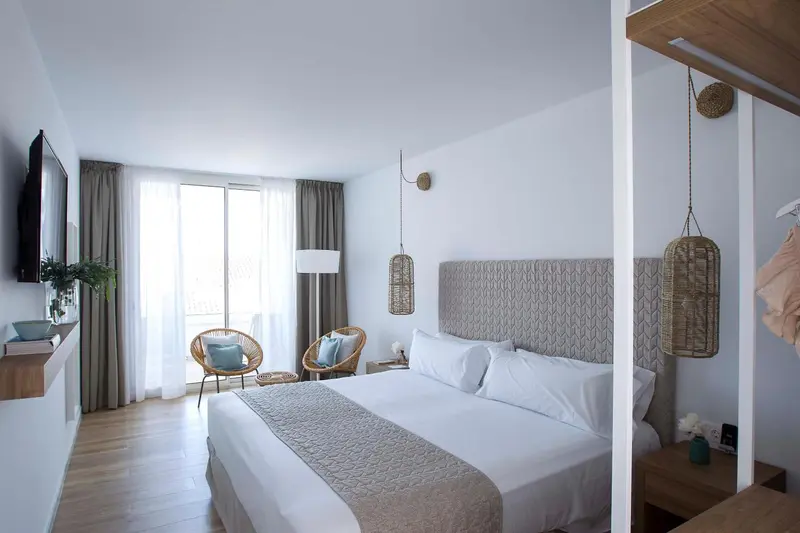 Une chambre lumineuse avec un grand lit et un coin salon.