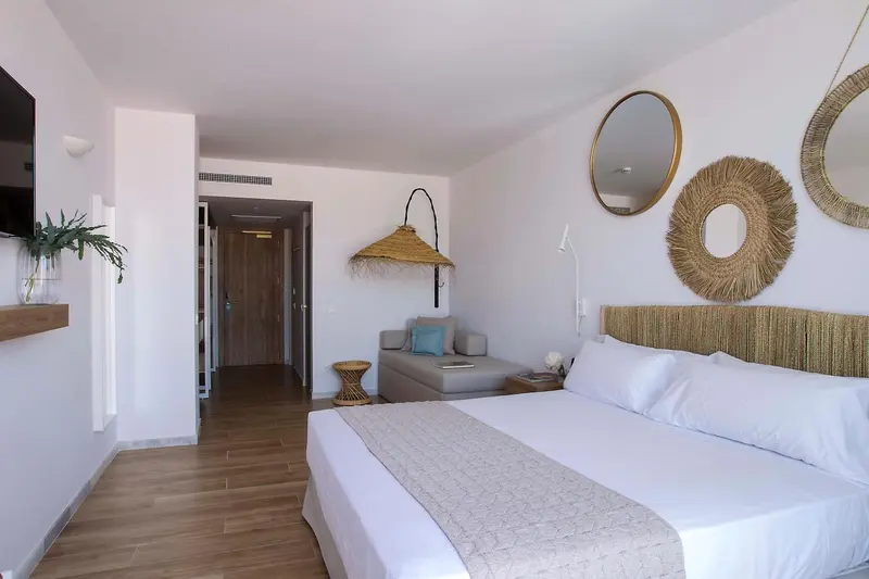 Chambre lumineuse avec un grand lit et une décoration murale en fibres naturelles.