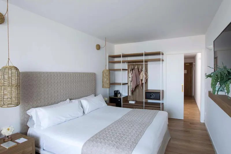 Une chambre lumineuse avec un grand lit et un espace de rangement ouvert.