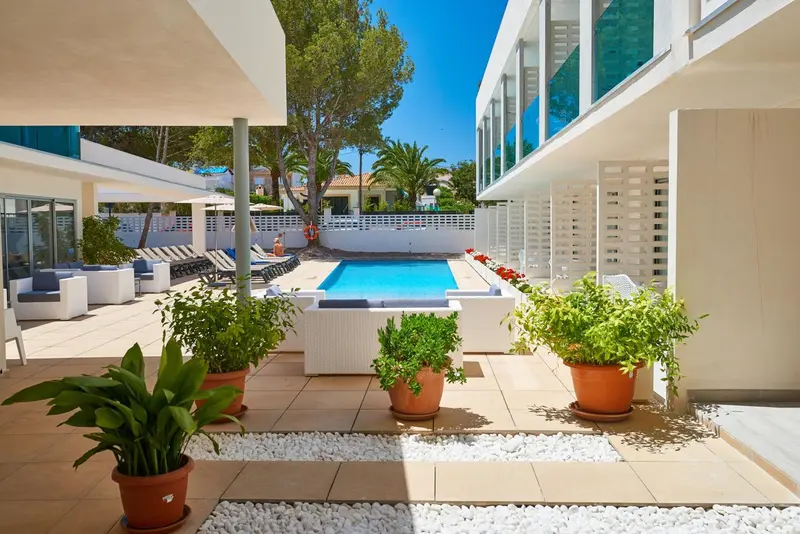 Une piscine rectangulaire est entourée d'un espace aménagé avec des plantes en pot et des meubles de jardin.