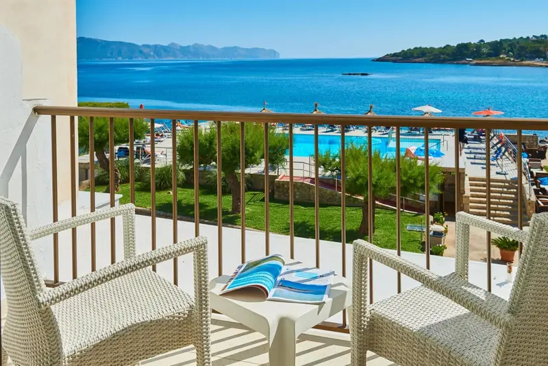 Vue d'une terrasse avec deux fauteuils et une table basse donnant sur une piscine et la mer.