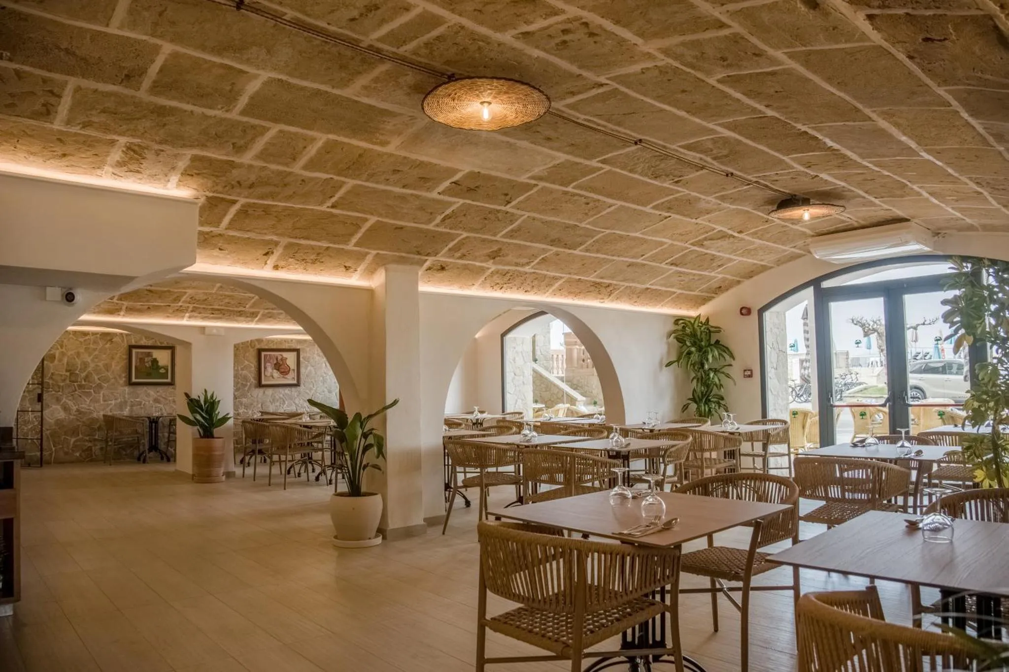 Une salle lumineuse avec des tables et des chaises en osier.