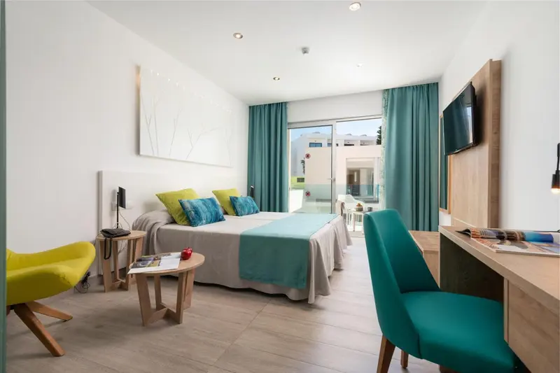 Une chambre lumineuse avec un lit double et un espace bureau.