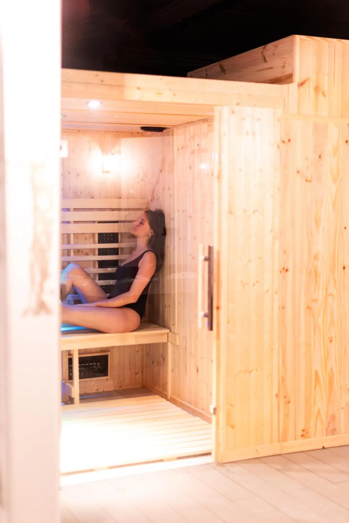 Une femme se détend dans un sauna en bois clair.