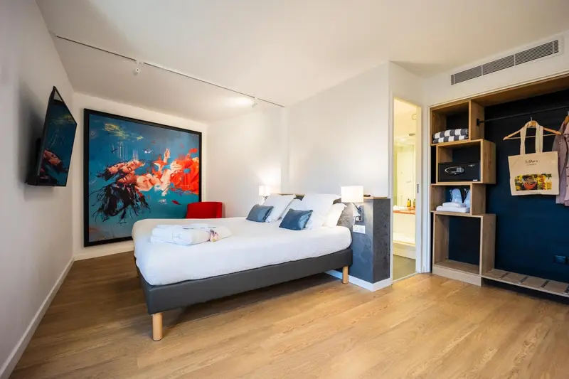 Une chambre lumineuse avec un grand lit et une décoration murale colorée.